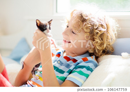 Child playing with kitten. Cat and kid at home. 106147759