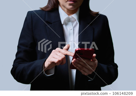 Closeup of business woman's hands using smartphone, on gray background 106148209