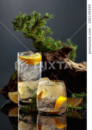Cocktail gin-tonic with ice and lemon on a black reflective background. 106148494