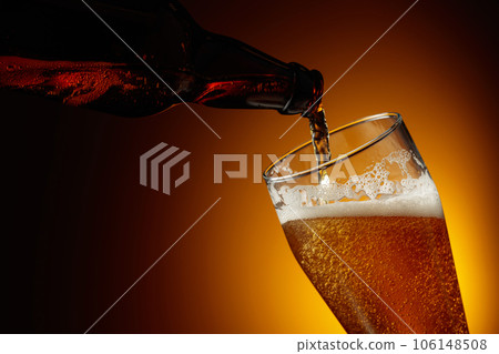 Pouring beer from a bottle into a glass. Pouring beer from a bottle into a glass. 106148508