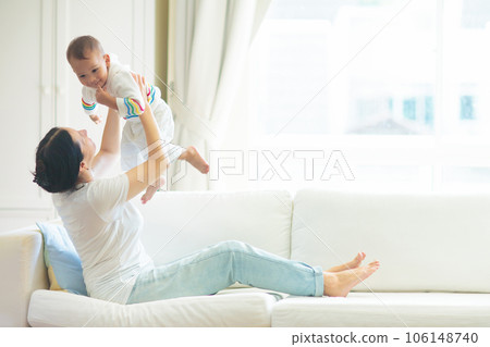 Mother and child on a white couch. 106148740