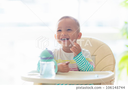 Baby eating solid foods in high chair. Baby eating solid foods in high chair. 106148744