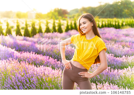 Fit girl wearing yellow t shirt posing in lavender field enjoying perfect summer morning. Fit girl wearing yellow t shirt posing in lavender field enjoying perfect summer morning. 106148785
