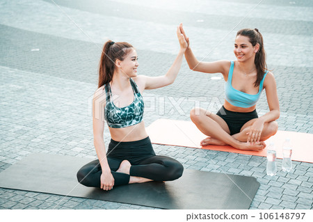Successful training. Two beautiful girls congratulate each other on great outdoor workout in the city by clapping their hands. 106148797