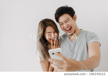Funny couple lover laugh at the clip in the smartphone isolated on white. 106149222