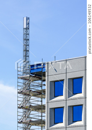 Repair works of a modern office building using scaffolding with temporary elevator platform 106149532