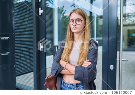 Portrait of young teenage student, trend girl in glasses looking at camera, outdoor 106150067