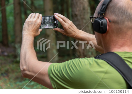 Berlin, Germany July 15 2023 Hands holding phone, taking photo, picture of forest nature 106150114