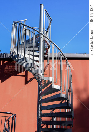Staircase and shadow. Gray metal stairs next to the wall of the orange building. Staircase and shadow. Gray metal stairs next to the wall of the orange building. 106151004