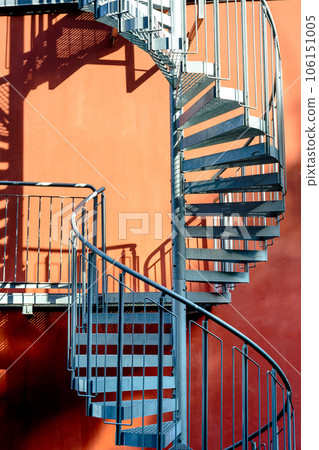 Staircase and shadow. Gray metal stairs next to the wall of the orange building. Staircase and shadow. Gray metal stairs next to the wall of the orange building. 106151005
