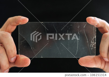 Broken protective glass for smartphone touch screen in hands of phone repairman on black background. Services for gluing and replacement of damaged protective glass. Repair concept 106151314