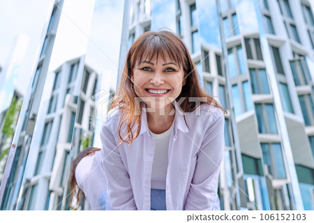 Happy mature woman looking at camera, in modern city of skyscrapers Happy mature woman looking at camera, in modern city of skyscrapers 106152103