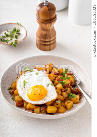 Potato, onion and ham hash topped with fried egg 106153329