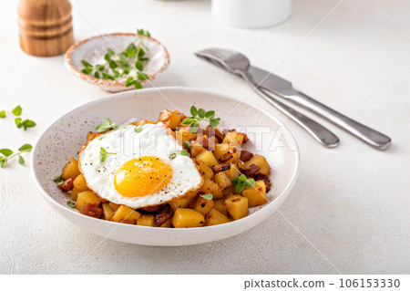 Potato, onion and ham hash topped with fried egg Potato, onion and ham hash topped with fried egg 106153330