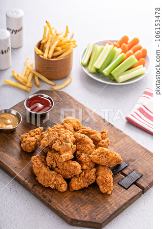 Fried chicken tenders or strips with sauces and fries Fried chicken tenders or strips with sauces and fries 106153478