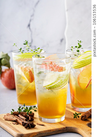 Refreshing apple cocktail or mocktail with ice and sliced apples 106153536