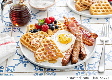Breakfast plate with waffles, fried egg, bacon and sausage Breakfast plate with waffles, fried egg, bacon and sausage 106153775