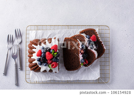 Chocolate pound cake topped with cream cheese glaze and berries Chocolate pound cake topped with cream cheese glaze and berries 106154928