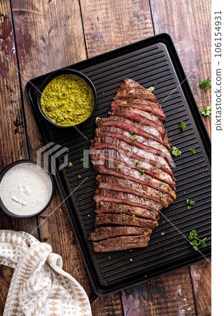 Grilled flank steak with chimichurri sauce on a grill pan 106154931