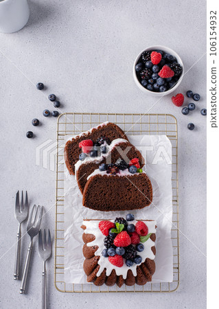 Chocolate pound cake topped with cream cheese glaze and berries 106154932