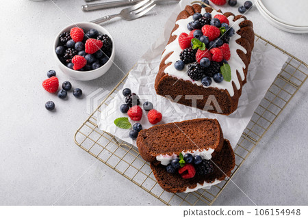 Chocolate pound cake topped with cream cheese glaze and berries 106154948