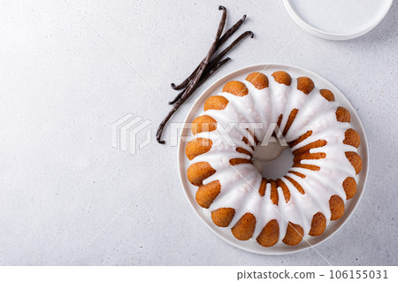 Vanilla bundt cake drizzled with powder sugar glaze 106155031