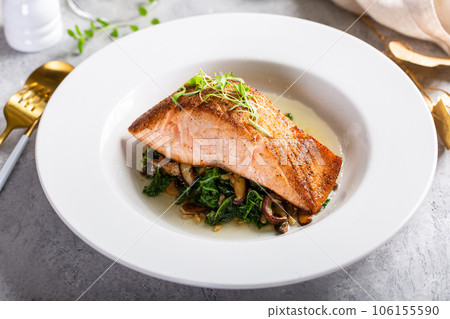 Salmon fillet served with sauteed greens and mushrooms Salmon fillet served with sauteed greens and mushrooms 106155590