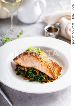 Salmon fillet served with sauteed greens and mushrooms 106155592