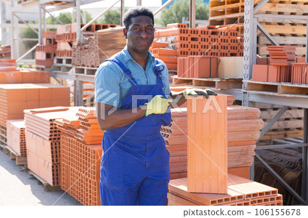 African american worker stacking bricks in warehouse of building materials at day 106155678