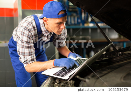 Mechanic man using laptop checking car in workshop Mechanic man using laptop checking car in workshop 106155679