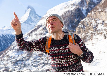 Traveler pointing at something while hiking with backpack in winter mountains 106155681