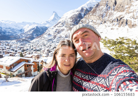 Cheerful man and woman making selfie during travel in Swiss Alps in winter 106155683