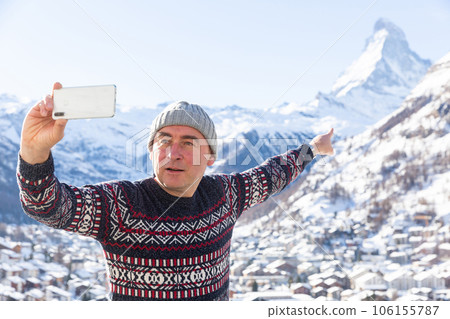 Travel blogger pointing at Matterhorn recording vlog with smartphone Travel blogger pointing at Matterhorn recording vlog with smartphone 106155787