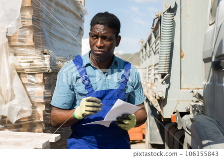 Worker checking order list standing near car at store 106155843