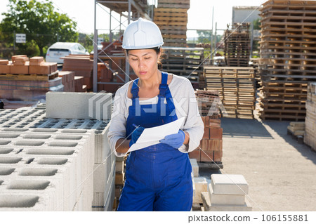 Asian female manager keeps records of brick in the open area of construction store Asian female manager keeps records of brick in the open area of construction store 106155881