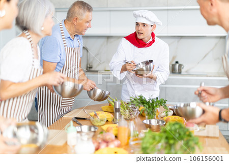 Young professional chef leading culinary courses to group of people 106156001