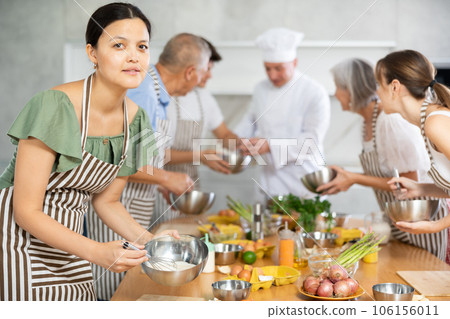 Young Asian woman mixing sauce in bowl at group culinary class Young Asian woman mixing sauce in bowl at group culinary class 106156011