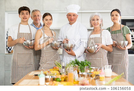 Smiling attendees of cooking course posing in kitchen while mixing sauce 106156058