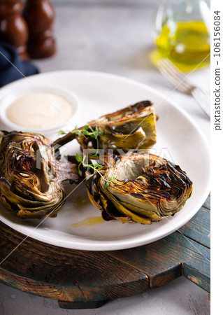 Grilled artichokes with a dipping sauce on a plate 106156084