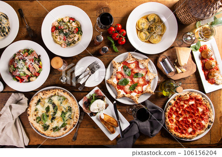Big dinner table with italian food, pizzas and pastas 106156204