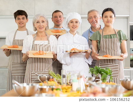 Group of cooks posing with salmon fillet on board Group of cooks posing with salmon fillet on board 106156252