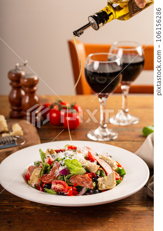 Italian antipasto salad with salami, artichoke hearts and olives 106156286
