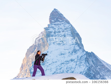 Woman photographer capturing mountain views of Swiss Alps with Matterhorn in background 106156366