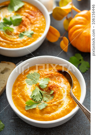 Pumpkin soup served with cream and cilantro 106156446
