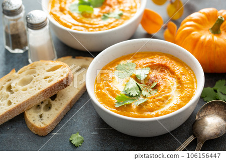Pumpkin soup served with cream and cilantro 106156447
