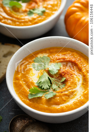 Pumpkin soup served with cream and cilantro 106156448