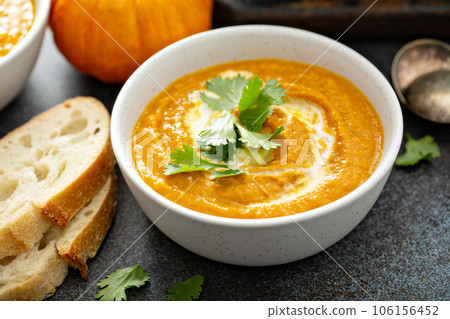 Pumpkin soup served with cream and cilantro 106156452