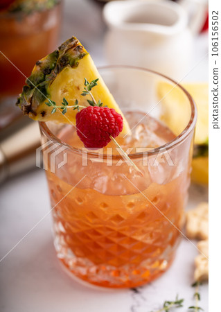 Raspberry pineapple refreshing cocktail with thyme sprig Raspberry pineapple refreshing cocktail with thyme sprig 106156502