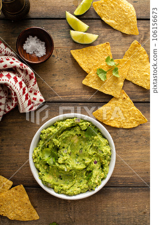 Chunky homemade guacamole in a bowl with tortilla chips 106156673