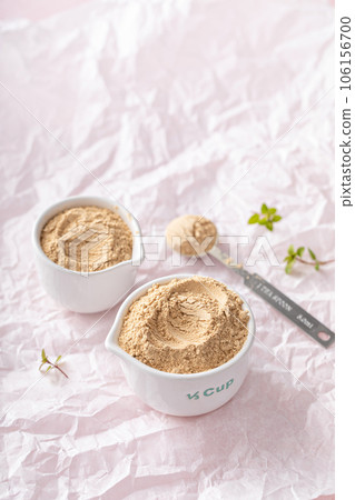Maca powder in measuring cups and a spoon 106156700